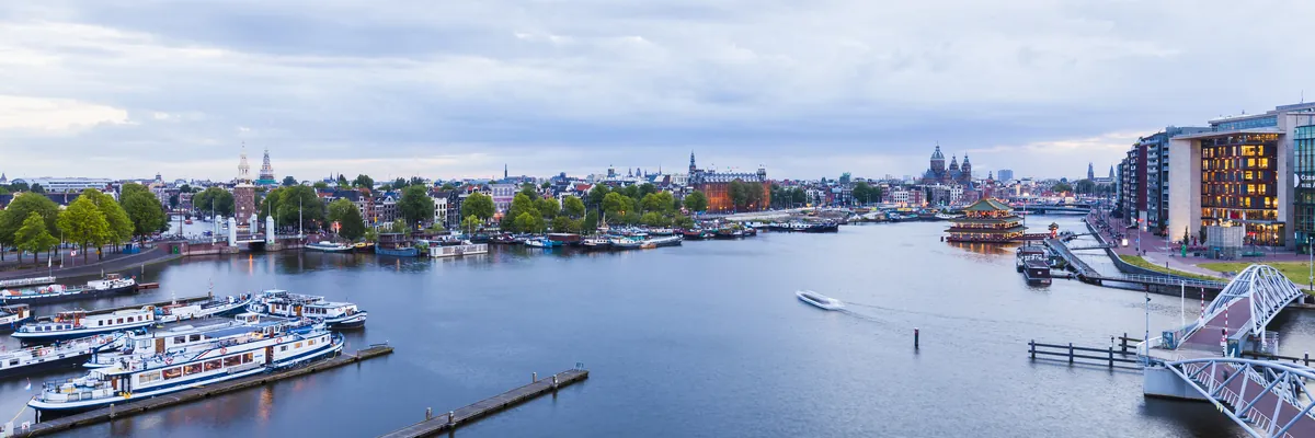 Amsterdam’s Oosterdok from above with tour boats and the old town skyline with the towers of St Nicholas Church