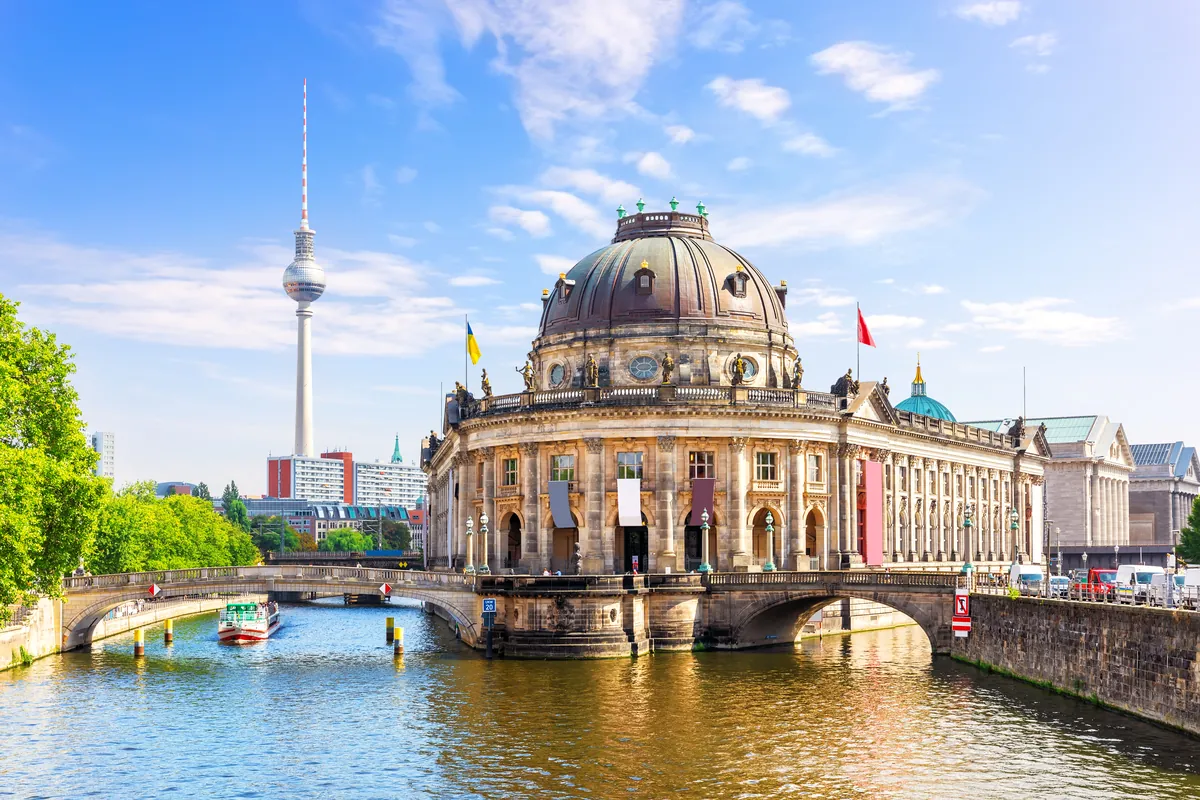 The Bode Museum at the tip of Museum Island in Berlin with the Spree, a small tour boat and the TV tower on a sunny day