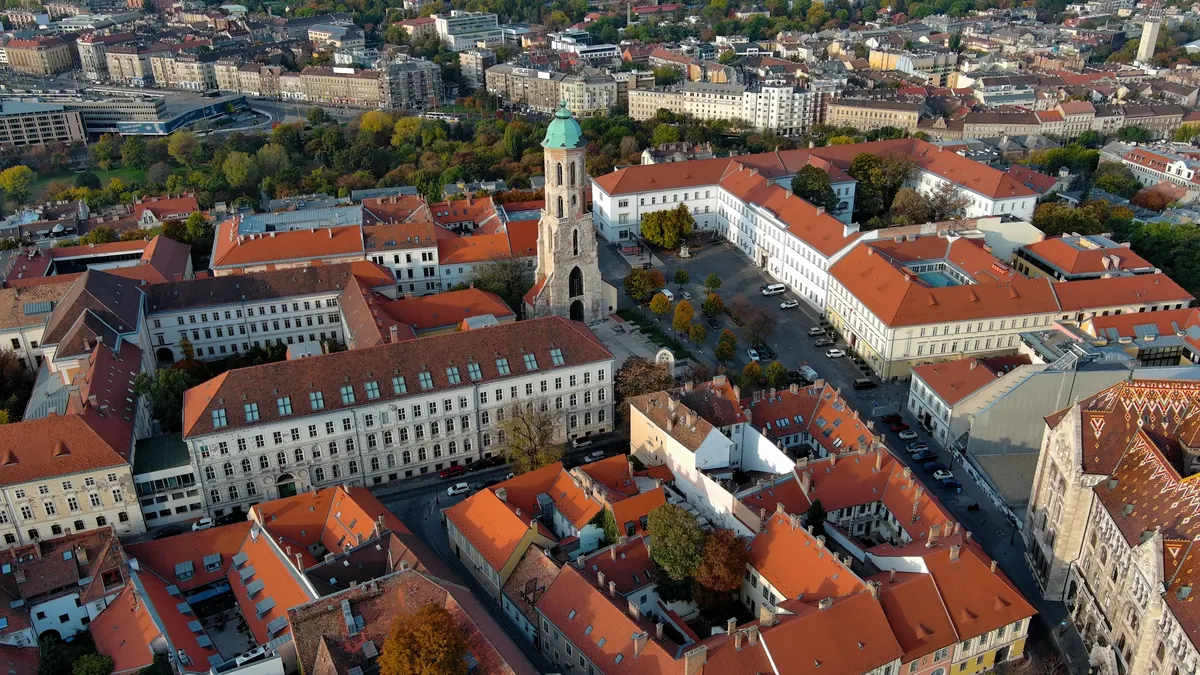 The Buda Castle District from above with the Mary Magdalene Tower, red-tiled roofs and autumn trees