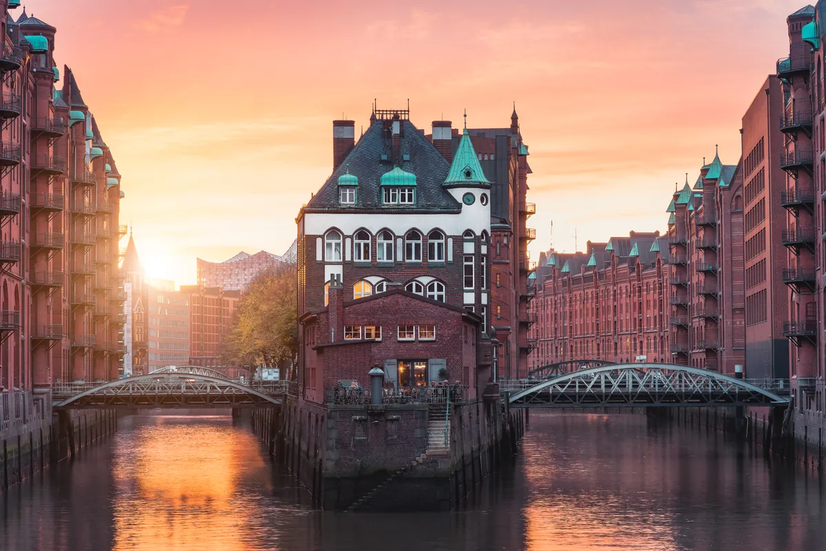 The brick warehouses and bridges of Hamburg’s Speicherstadt reflected in the canal at sunset