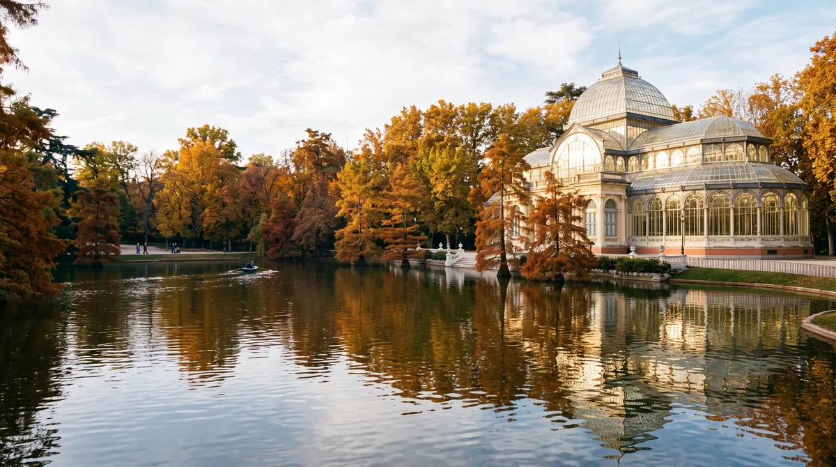 A 19th century glass and iron pavilion beside a small lake in Madrid’s Retiro Park, autumn trees reflected in the water