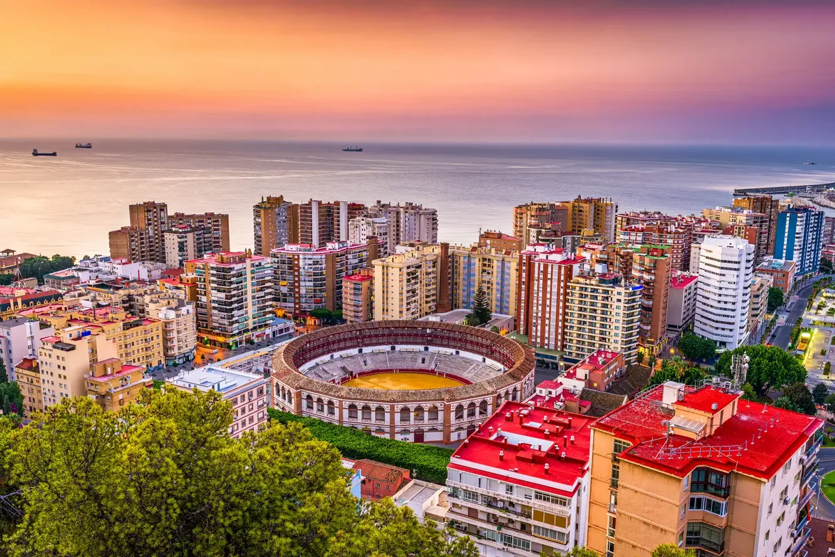 Málaga at sunset from above, the round bullring, the apartment blocks of La Malagueta and the sea